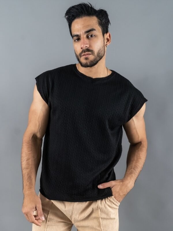 Hombre vistiendo polo negro Manica Zero de Ezzeta, con diseño sin mangas y estilo urbano.