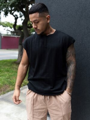 Hombre vistiendo polo negro Manica Zero de Ezzeta, con diseño sin mangas y estilo urbano.
