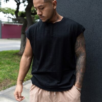 Hombre vistiendo polo negro Manica Zero de Ezzeta, con diseño sin mangas y estilo urbano.