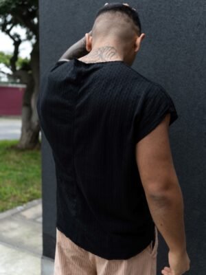 Hombre vistiendo polo negro Manica Zero de Ezzeta, con diseño sin mangas y estilo urbano.