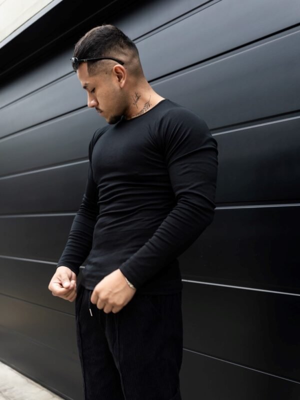 Hombre vistiendo polo negro Maniche Lunche Large de Ezzeta, con mangas largas y estilo casual.